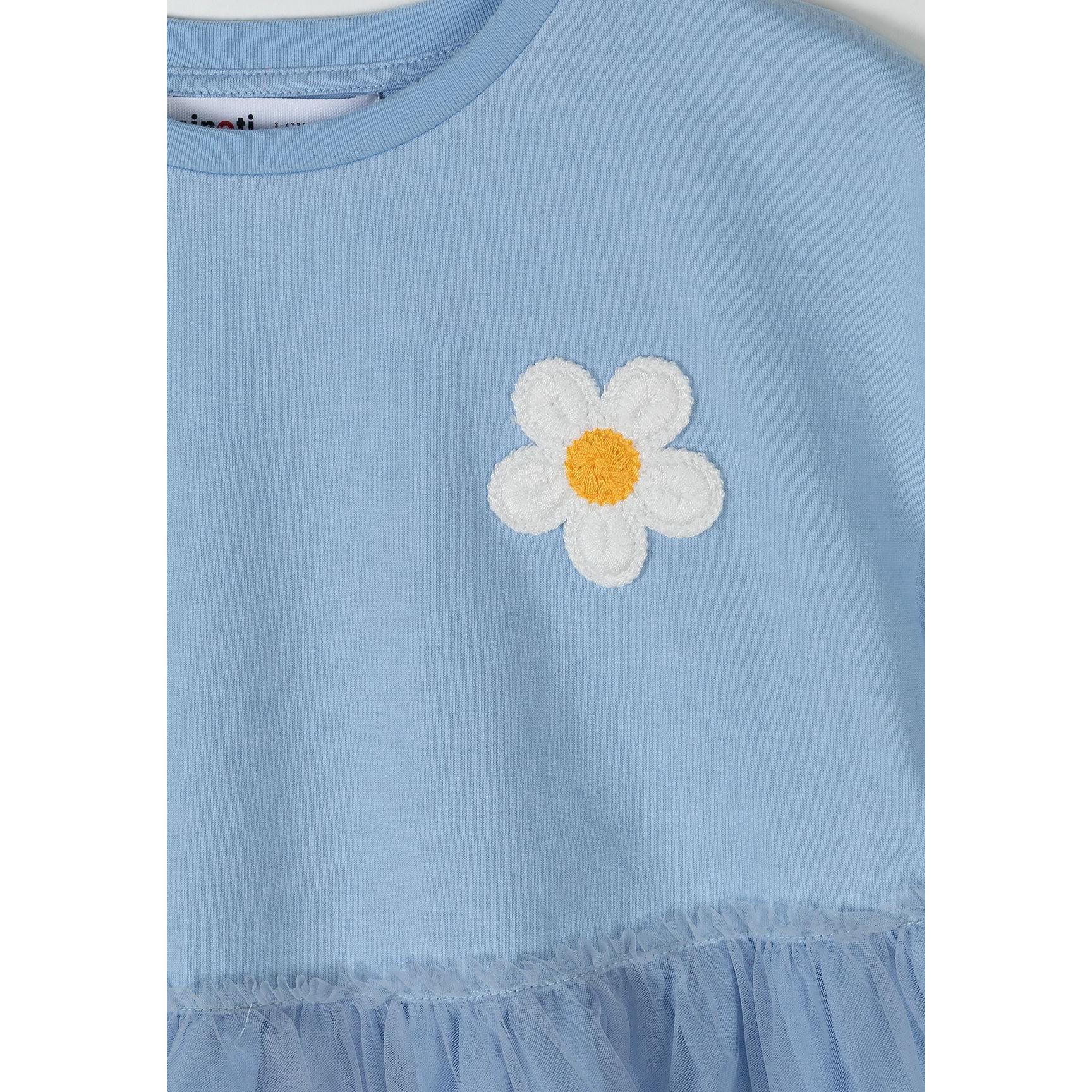 Close-up detail of white embroidered daisy flower on blue cotton jersey bodice with Minoti brand label visible