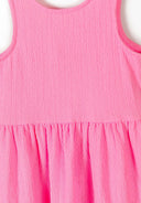Close-up of a pink sleeveless tiered summer dress with textured fabric.