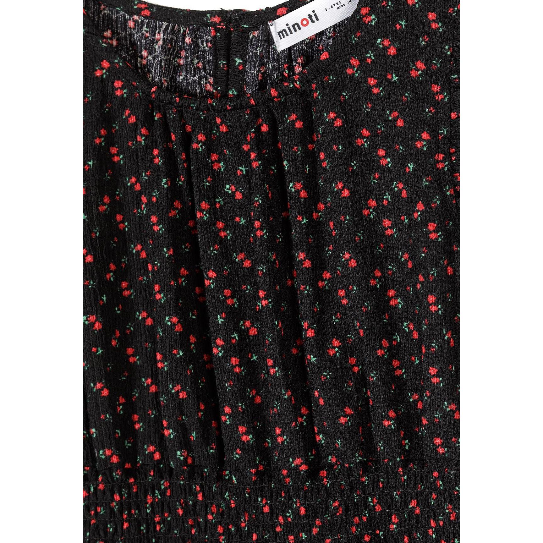 Close-up detail shot of black fabric with tiny red floral print pattern and Minoti brand label visible, showing texture and print quality