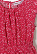 Close-up of pink floral fabric with frill sleeves and elasticated waistband showing detailed design and texture