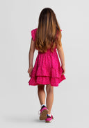 Young girl wearing a pink floral dress with tiered skirt and frill sleeves, showcasing a stylish kids fashion design.