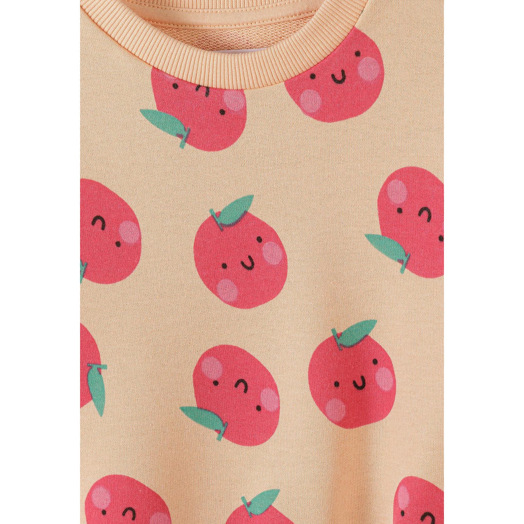 Detail shot of apricot sweatshirt showing cute kawaii-style apple print with smiling faces, green leaves and ribbed neckline