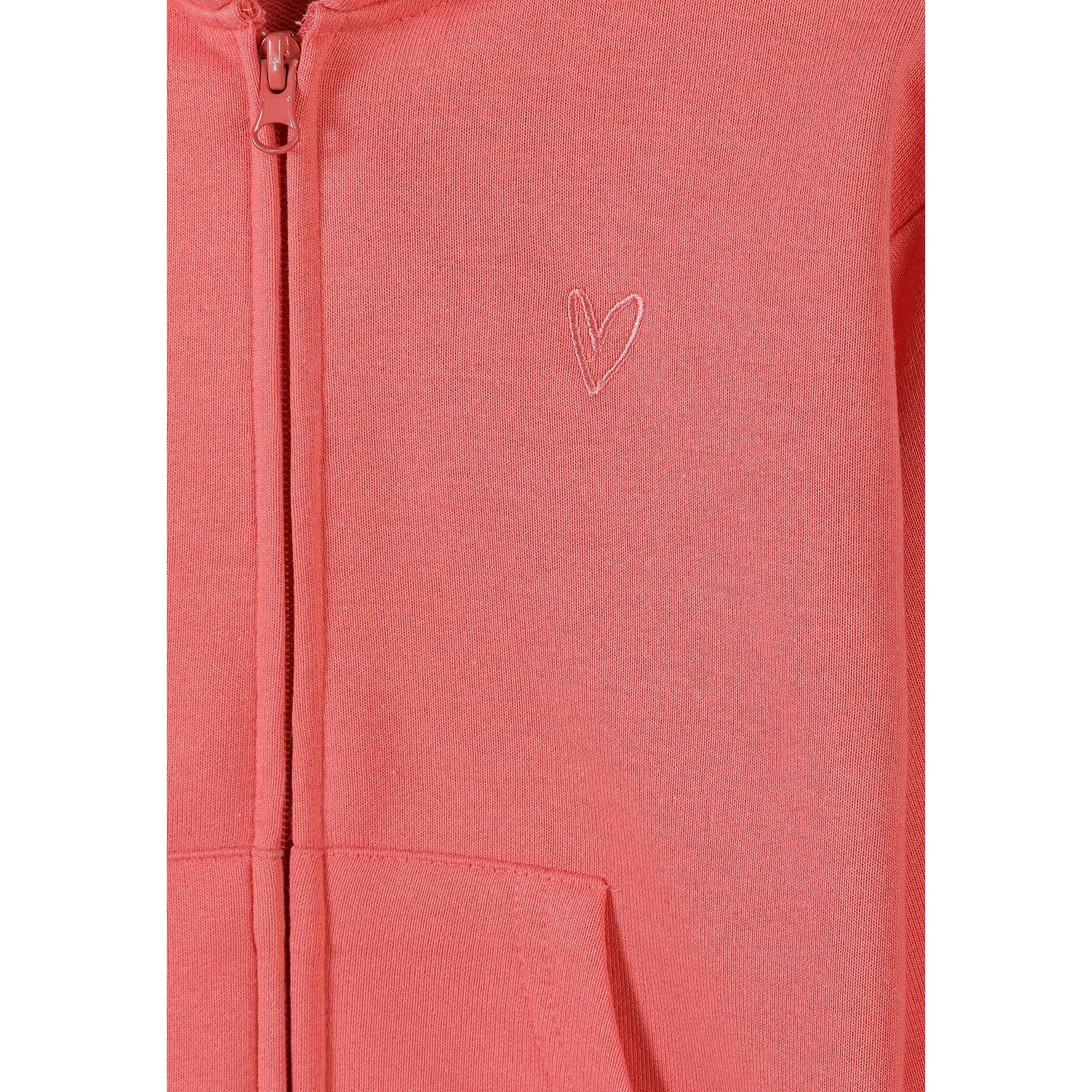 Detail view showing embroidered white heart design on coral pink hoodie fabric with zip visible on left side