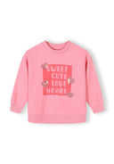 Girls pink sweatshirt with long sleeves and heart print, front view.