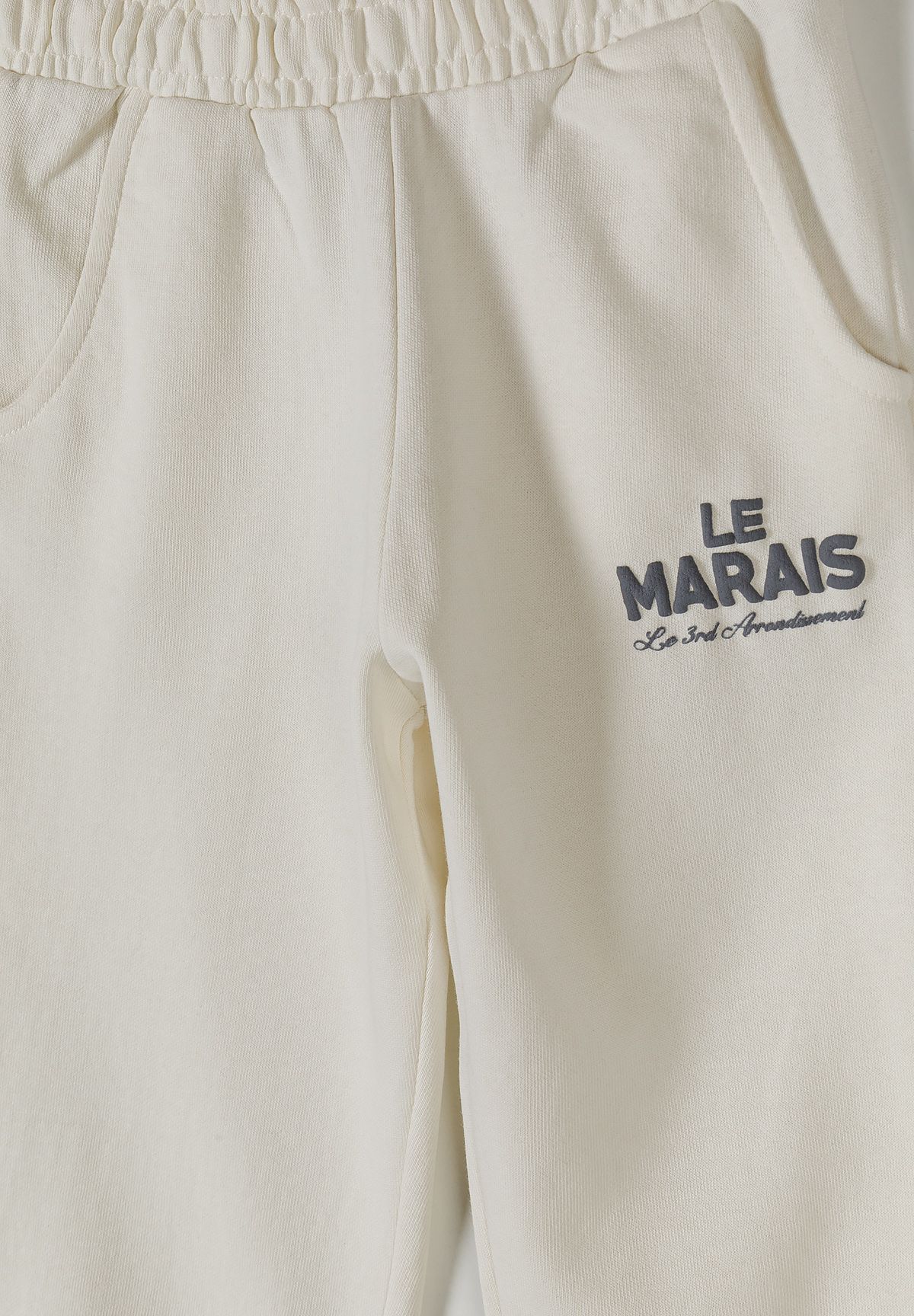 Detail of off-white joggers with side pockets and logo embroidery.