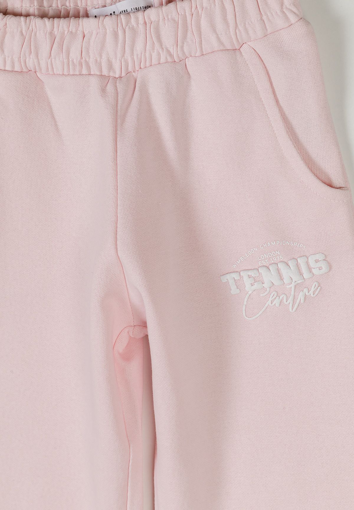 Detail of light pink joggers with elasticated waistband and side pockets.