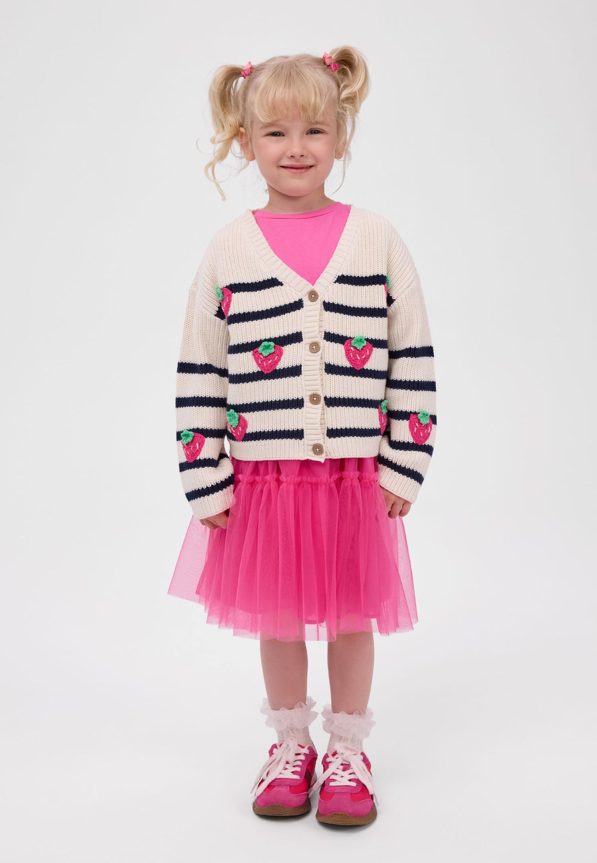 Girl wearing ivory and navy striped V-neck cardigan with pink strawberries.