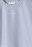 Close-up of blue girls sweatshirt with embroidered chest detail and crew neck, showcasing delicate kids fashion design.