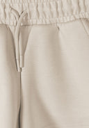 Close-up of beige elasticated waist shorts with drawstring, highlighting the soft fabric and simple design for kids fashion.