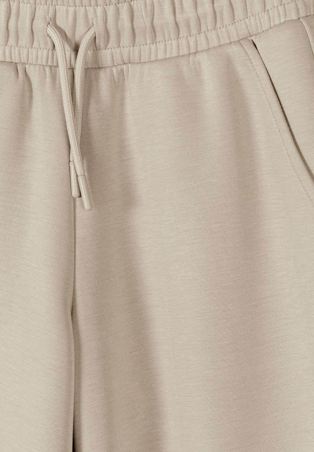 Beige wide-leg cargo trousers, waist and pocket detail.