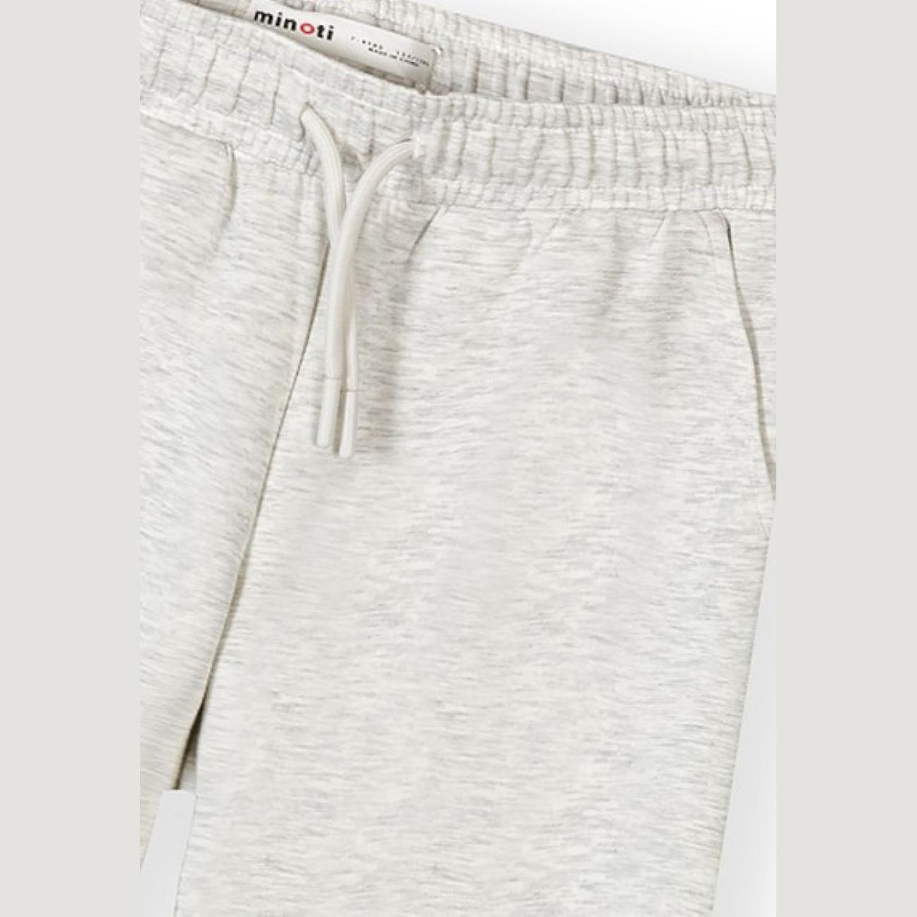 Close-up detail of grey melange joggers showing Minoti brand label, drawstring ties and fabric texture