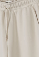 Close-up of beige wide leg jogger with elastic waistband and drawstring detail in soft viscose fabric