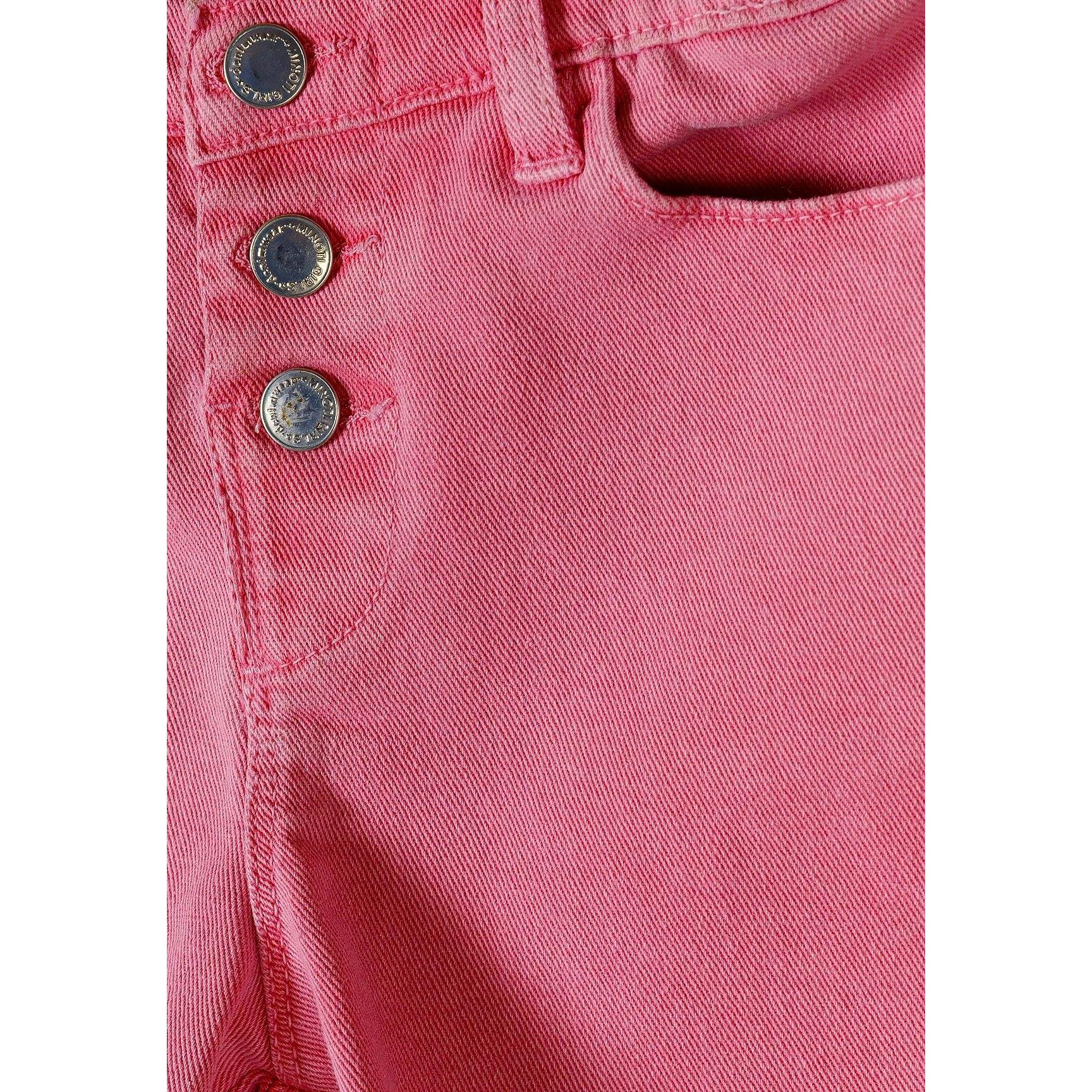 Close-up detail of three decorative metal buttons and cotton twill fabric texture on pink shorts