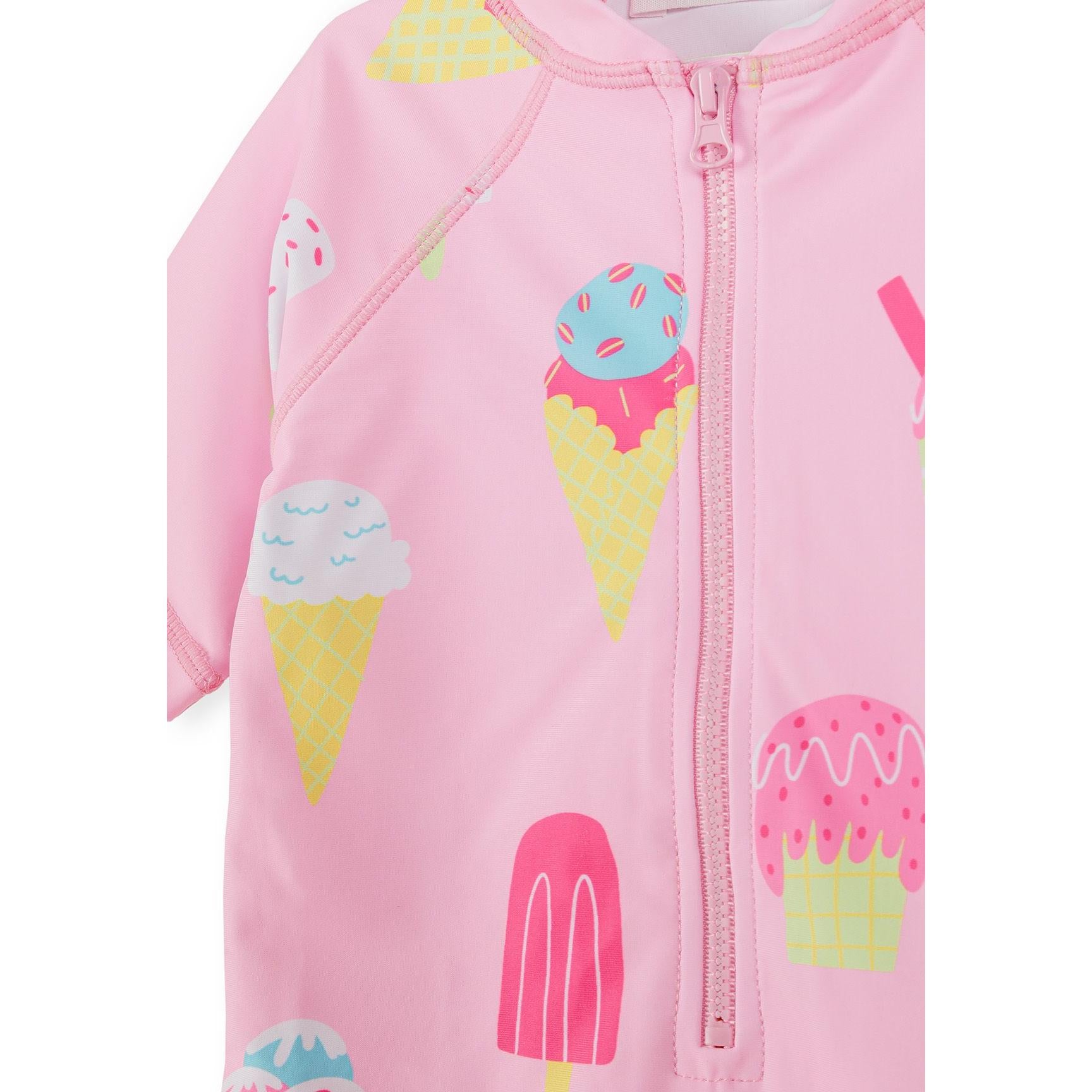 Close-up detail of pink rashguard showing ice cream cone graphics and zip closure construction against white background