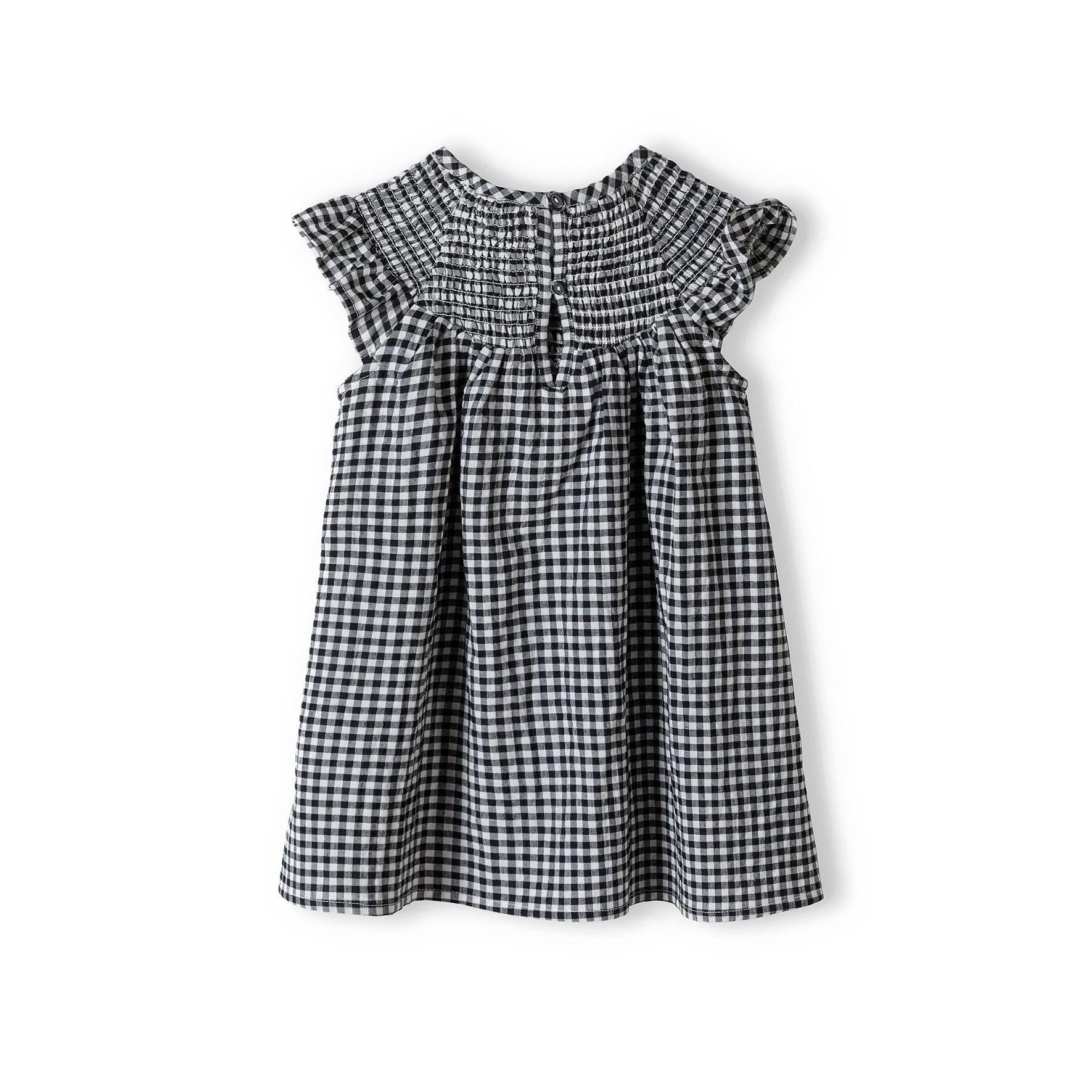 Grey gingham smock dress laid flat on white background showing frill sleeve details, shirred neckline and overall construction