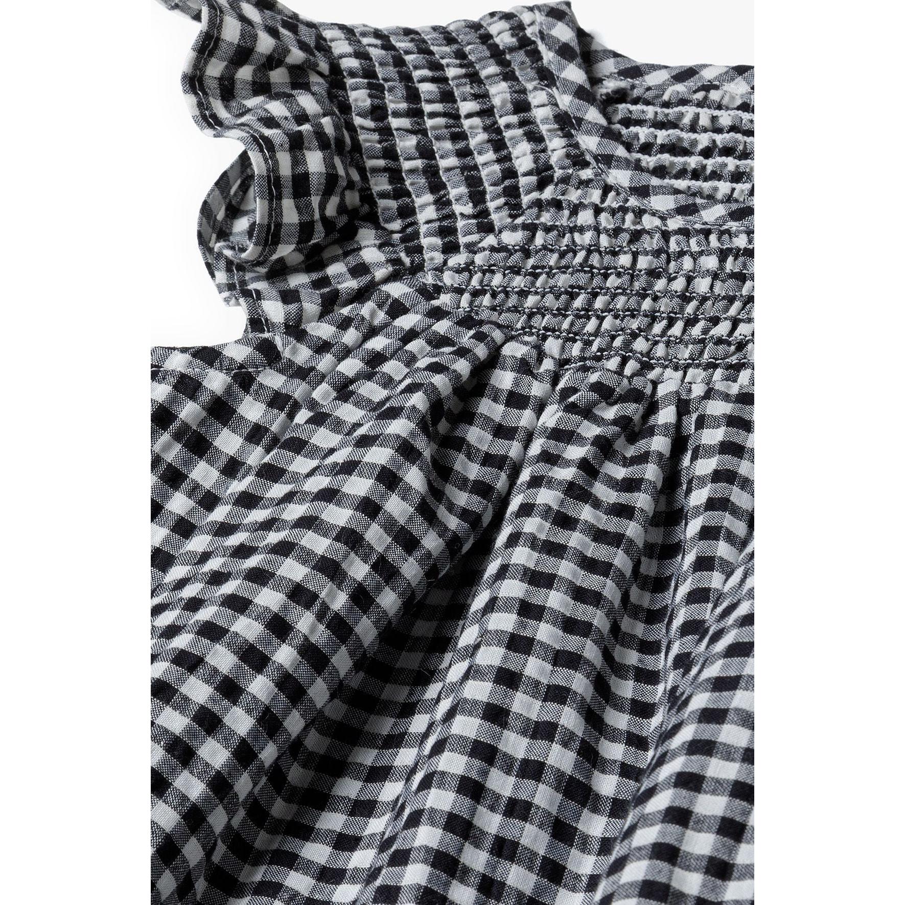 Close-up detail of grey gingham fabric texture and shirred neckline construction showing fabric quality and stitching details
