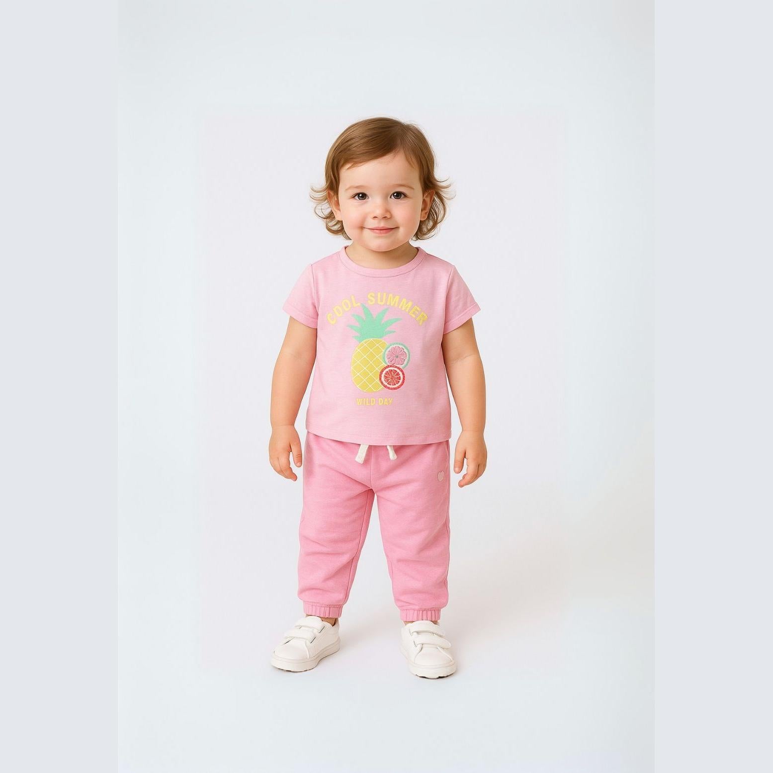 Toddler wearing light pink slub t-shirt with Cool Summer crochet pineapple applique and matching pink joggers, standing against white background