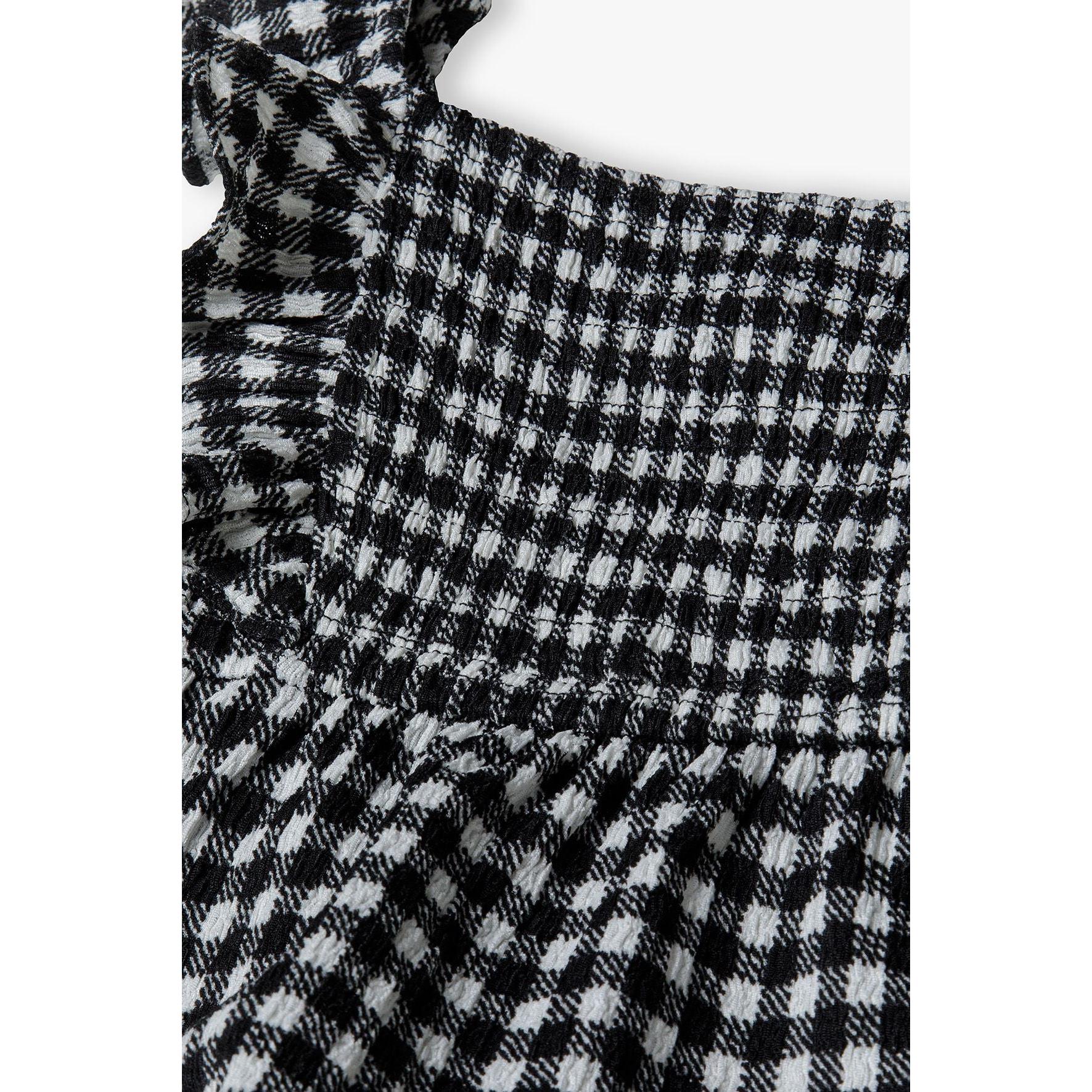Close-up detail of black and white gingham fabric texture and shirred bodice construction with gathered elastic panels