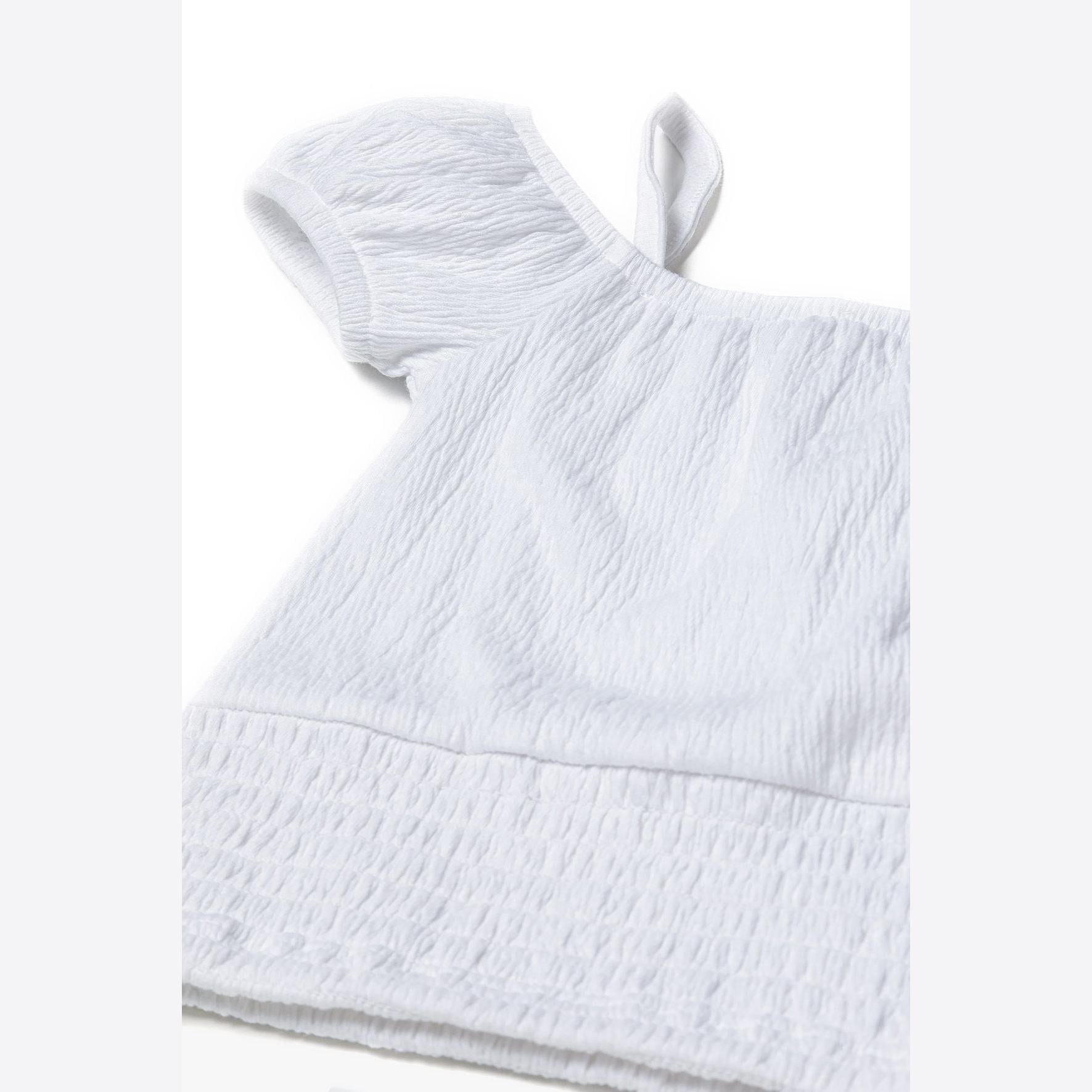 White textured off shoulder top photographed at angle showing three-dimensional shape and fabric texture with elasticated hem detail