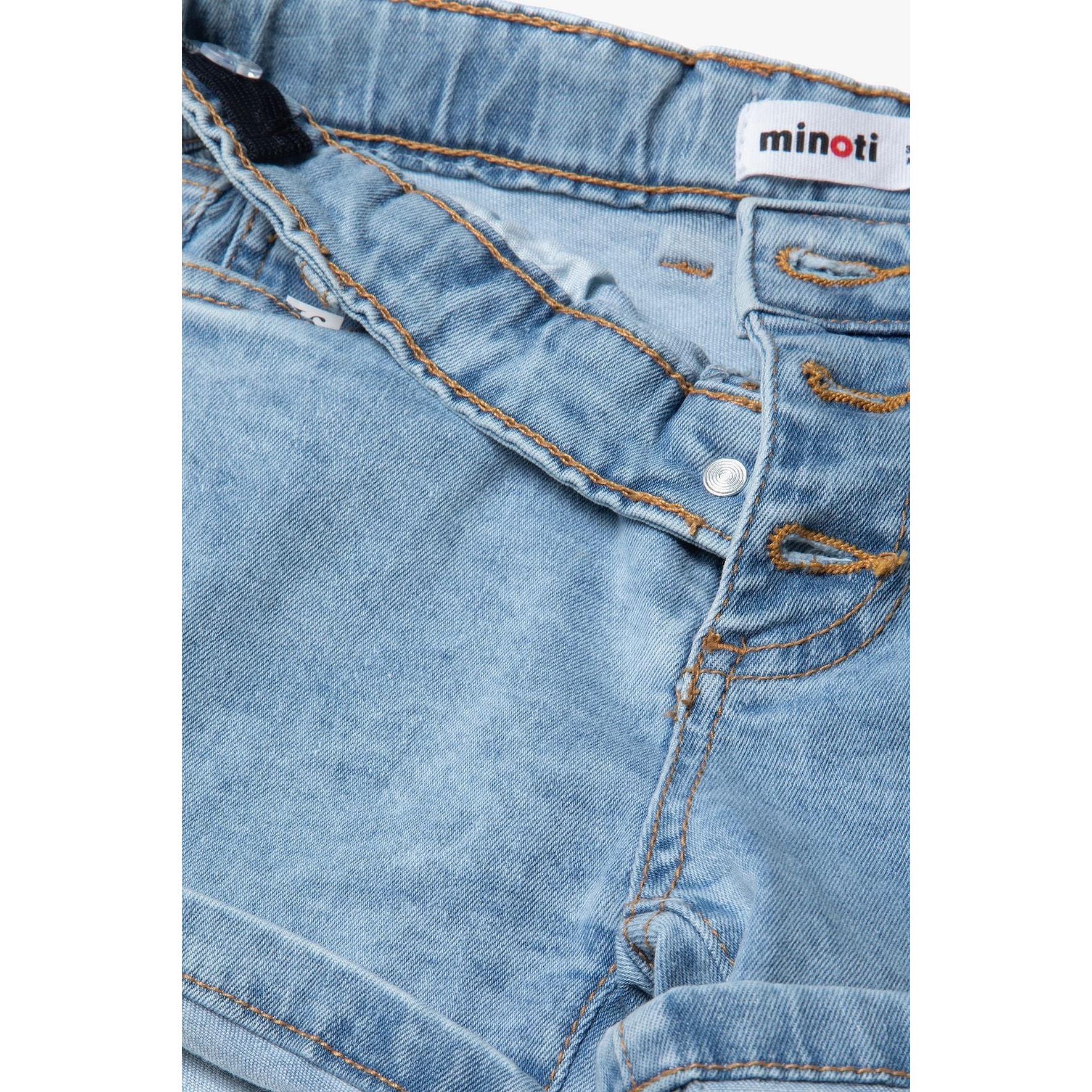 Close-up detail of light blue denim shorts showing three-button fly fastening, Minoti brand label, and front pocket construction