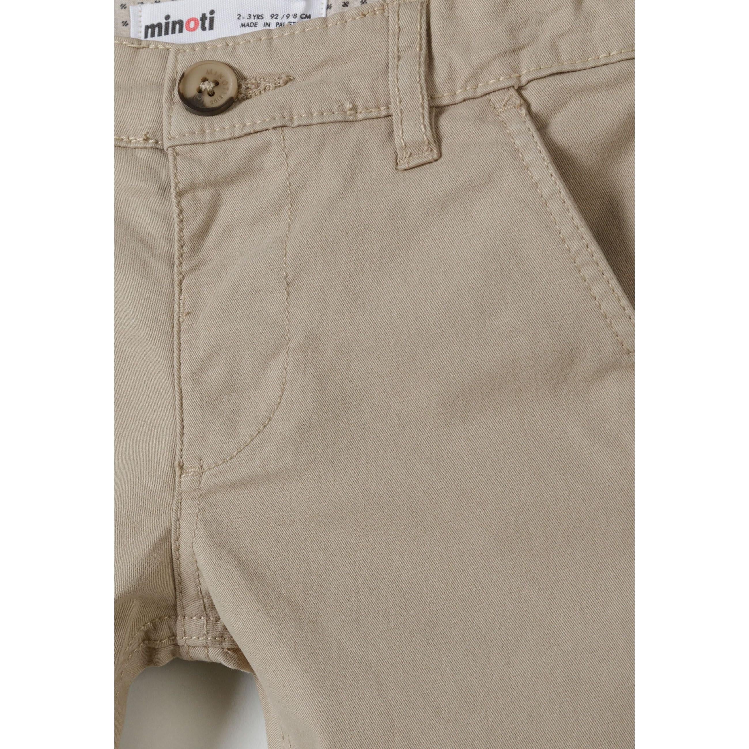 Close-up detail of grey chino trousers showing Minoti label, button fastening, front pocket and cotton fabric texture