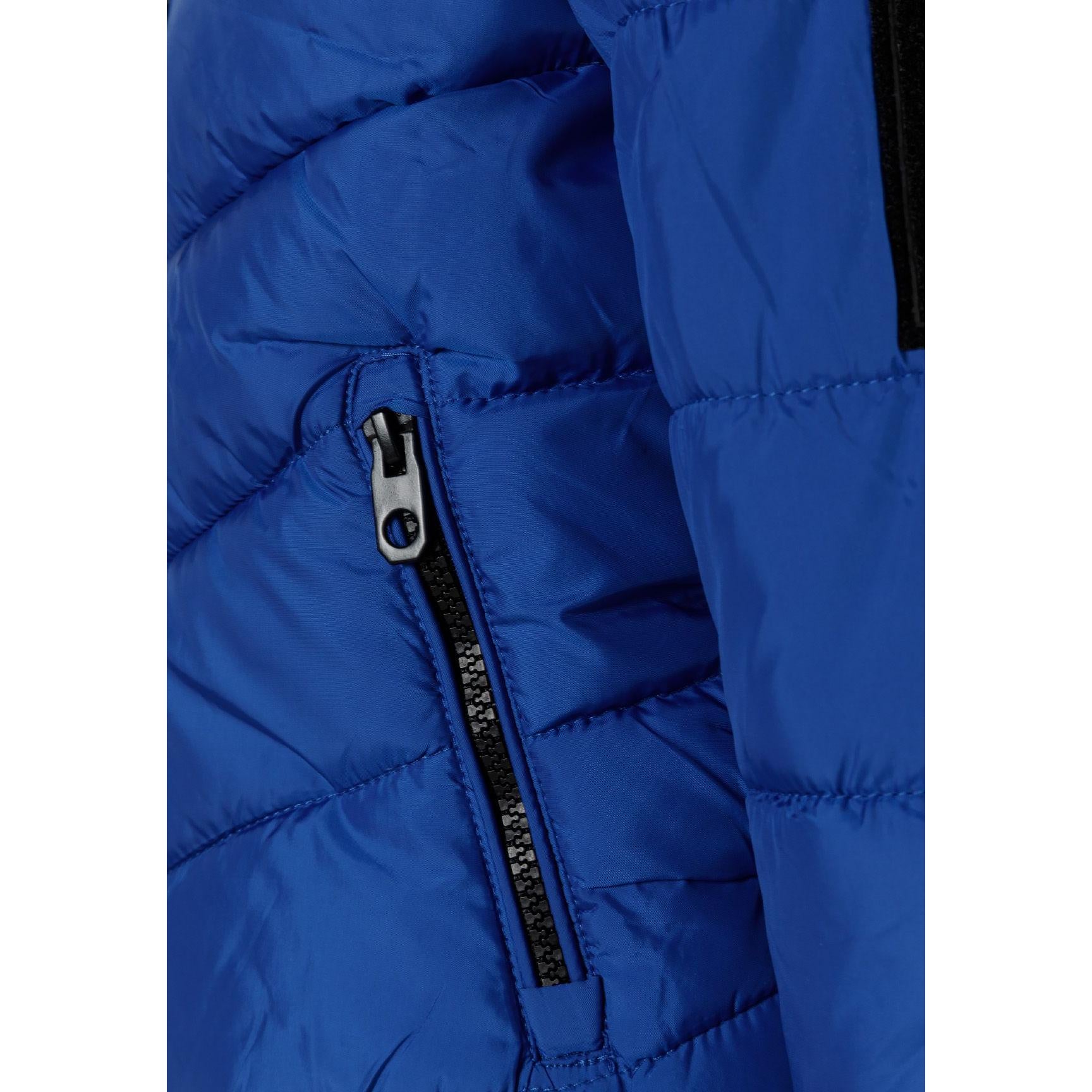 Close-up detail of black fabric label on cobalt blue jacket showing MNT brand text and authenticity information