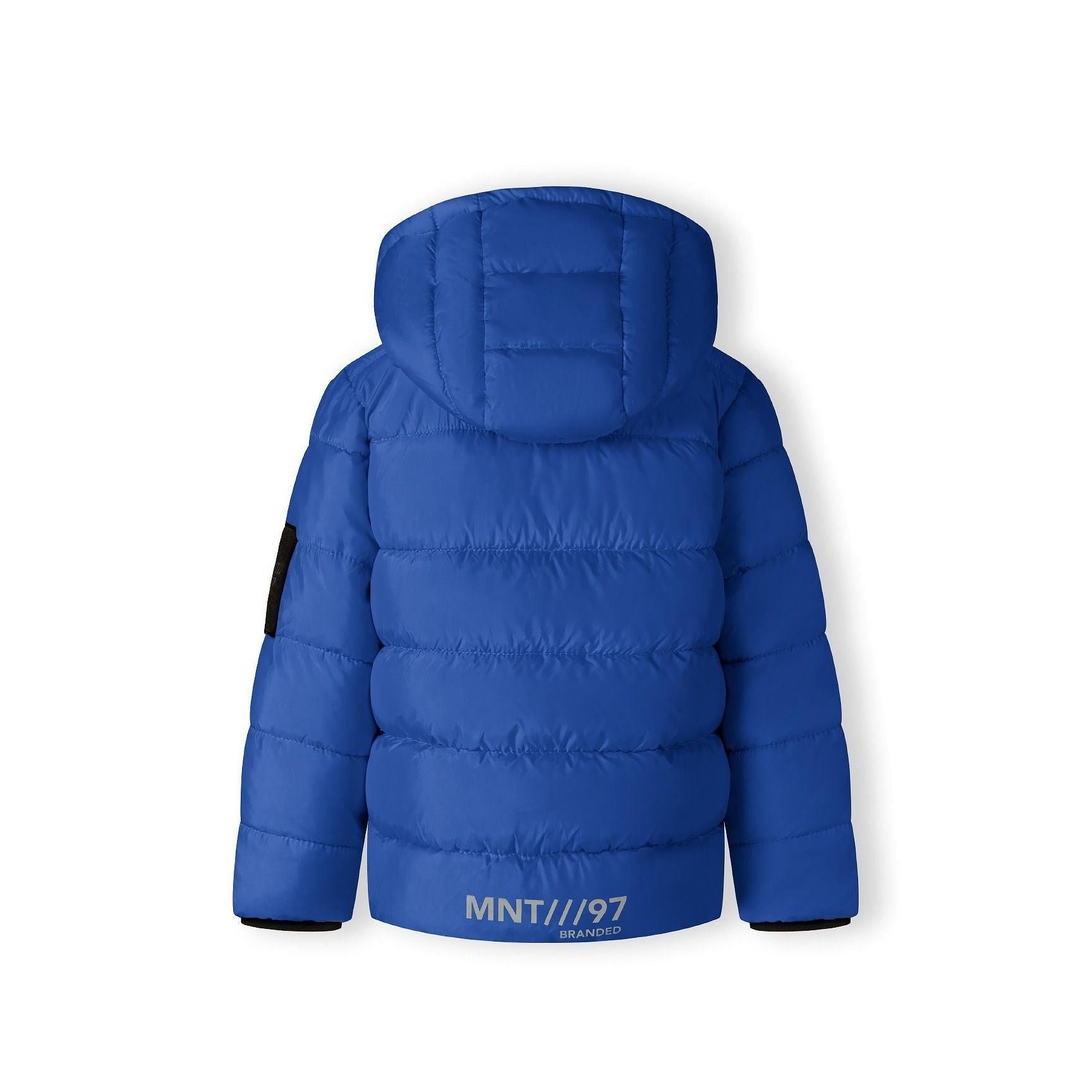 Close-up detail of black fabric label on cobalt blue jacket showing MNT brand text and authenticity information