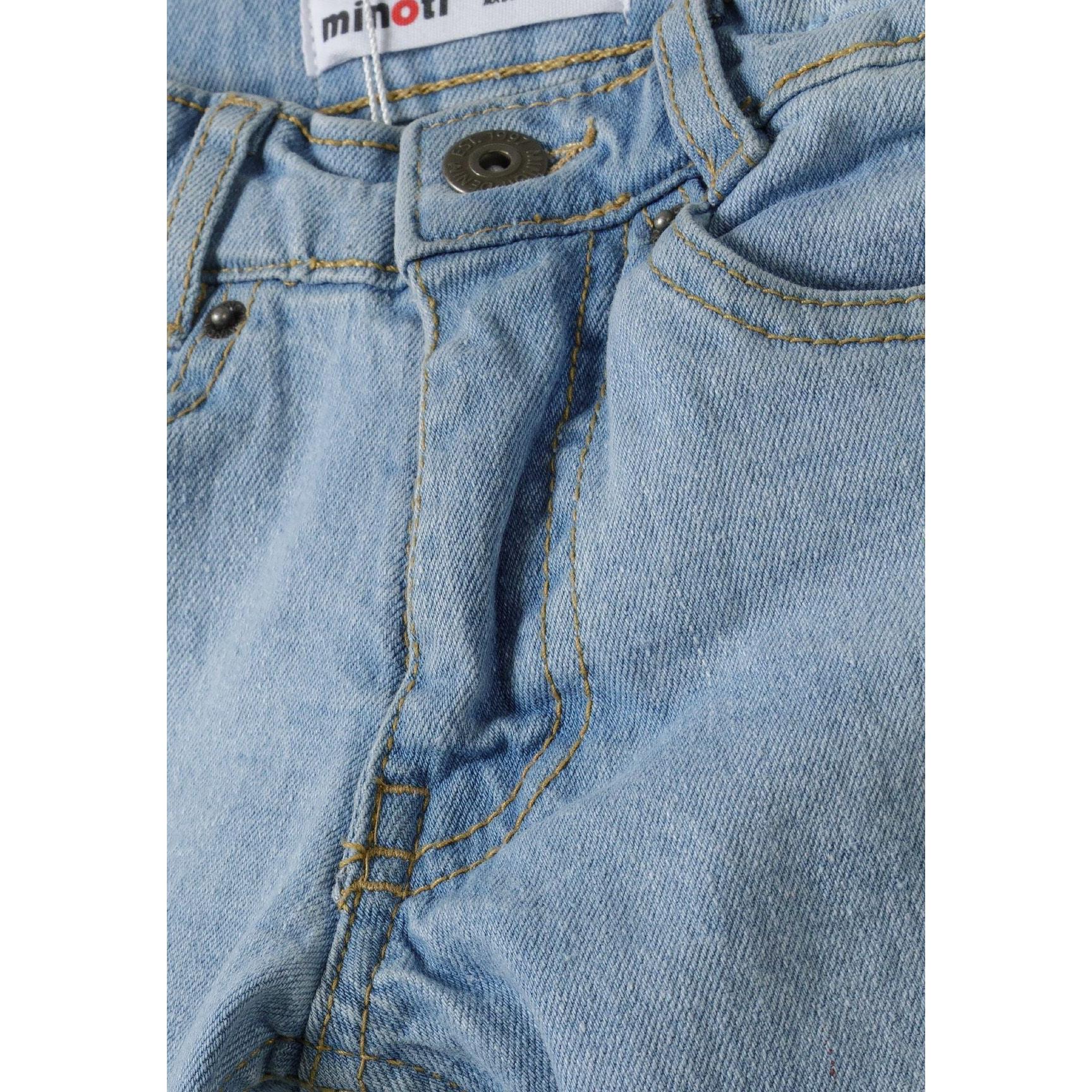 Close-up detail of light blue denim jeans showing Minoti brand label, button closure and front pocket stitching