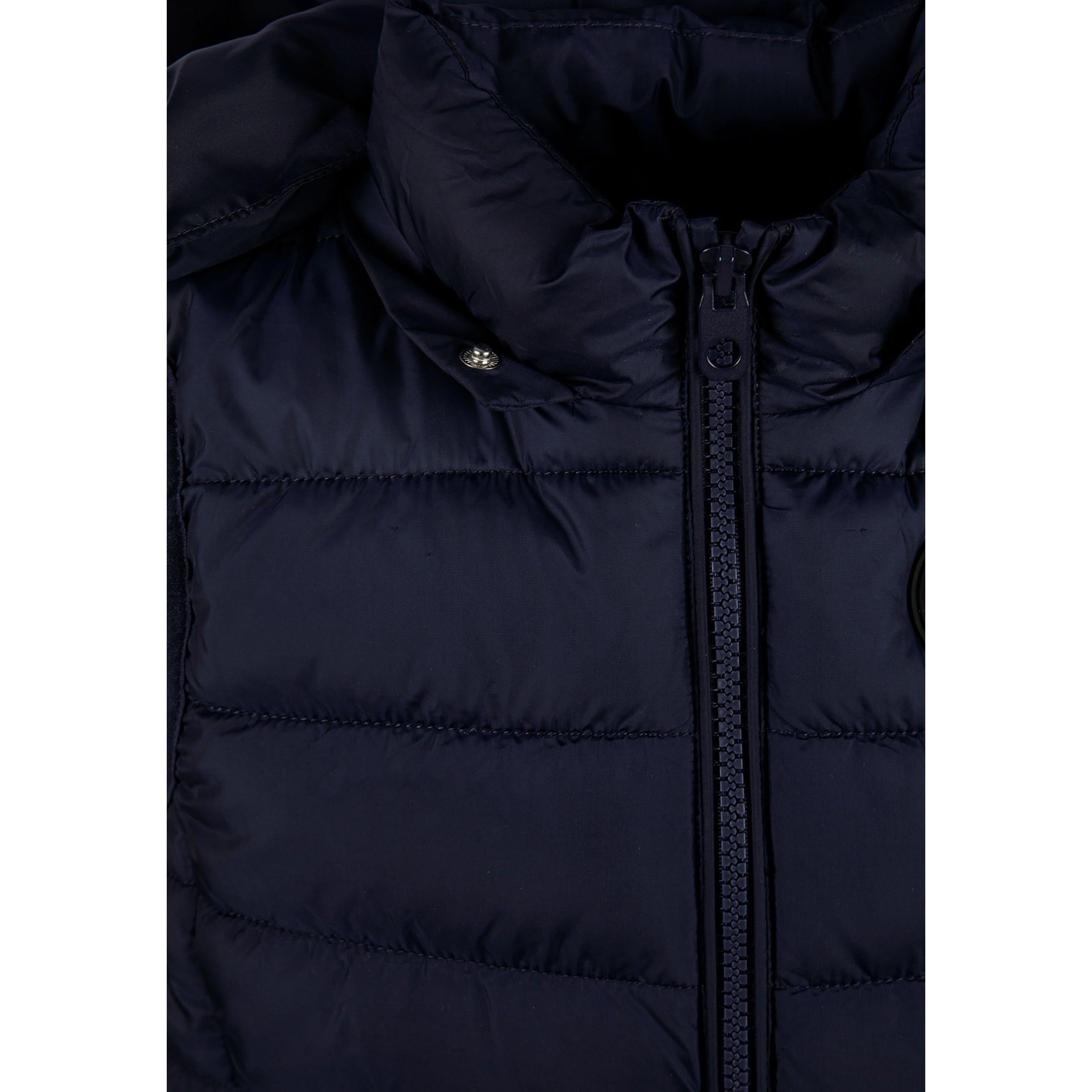 Close-up detail of navy padded gilet showing full zip closure, quilted panels and fabric texture on dark background