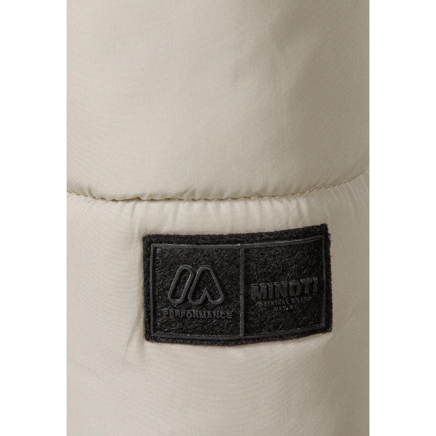 Close-up detail of cream padded jacket showing black branded patch with mountain logo and Minoti text on sleeve