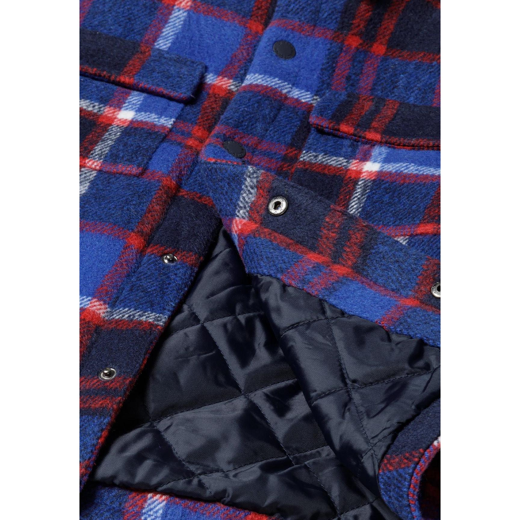 Close-up detail of blue check fabric pattern with black quilted lining visible through open front closure