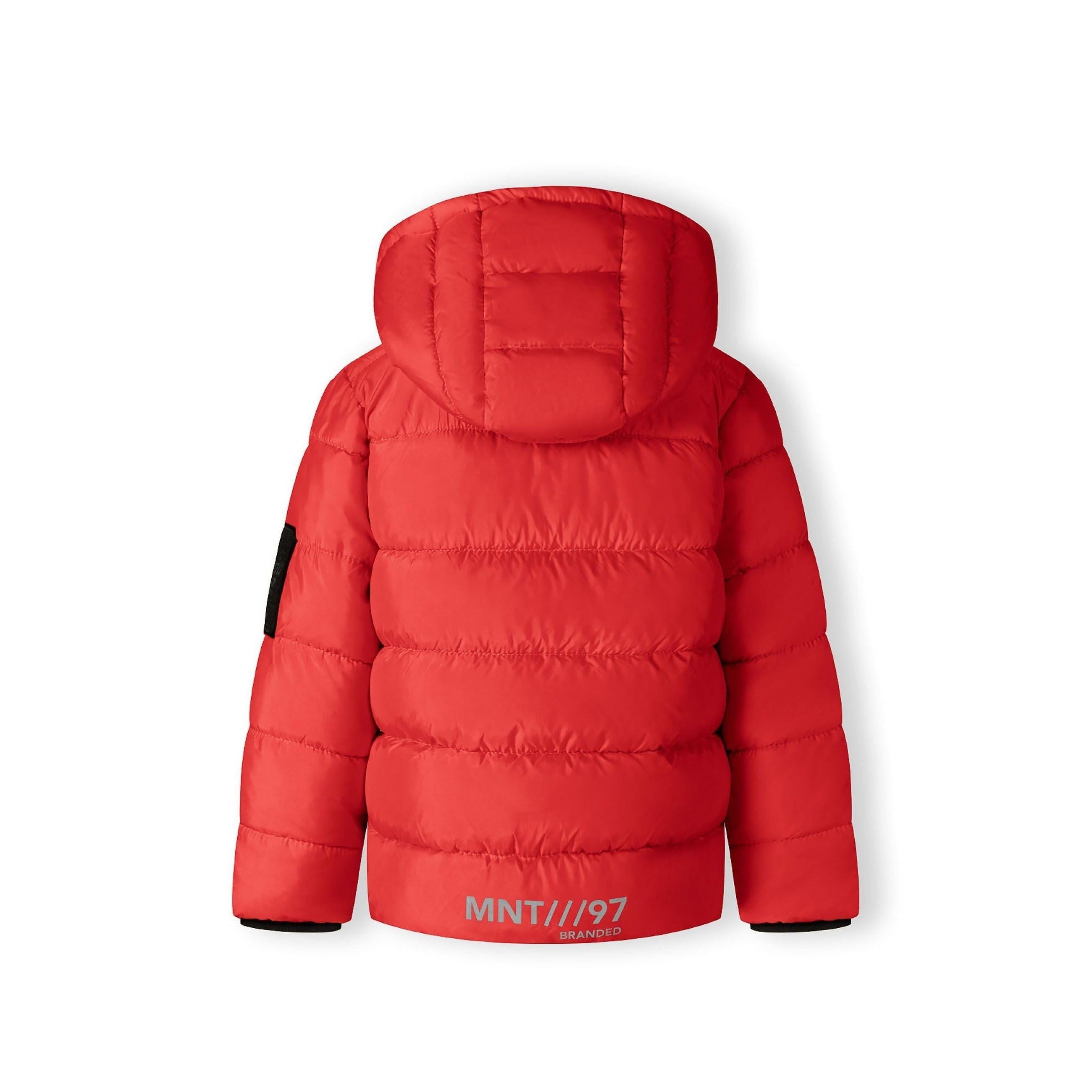 Close-up detail of black Minoti brand patch on red quilted jacket fabric showing logo and text