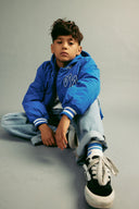 chłopiec w niebieskiej kurtce i spodniami z szerokimi spodniami