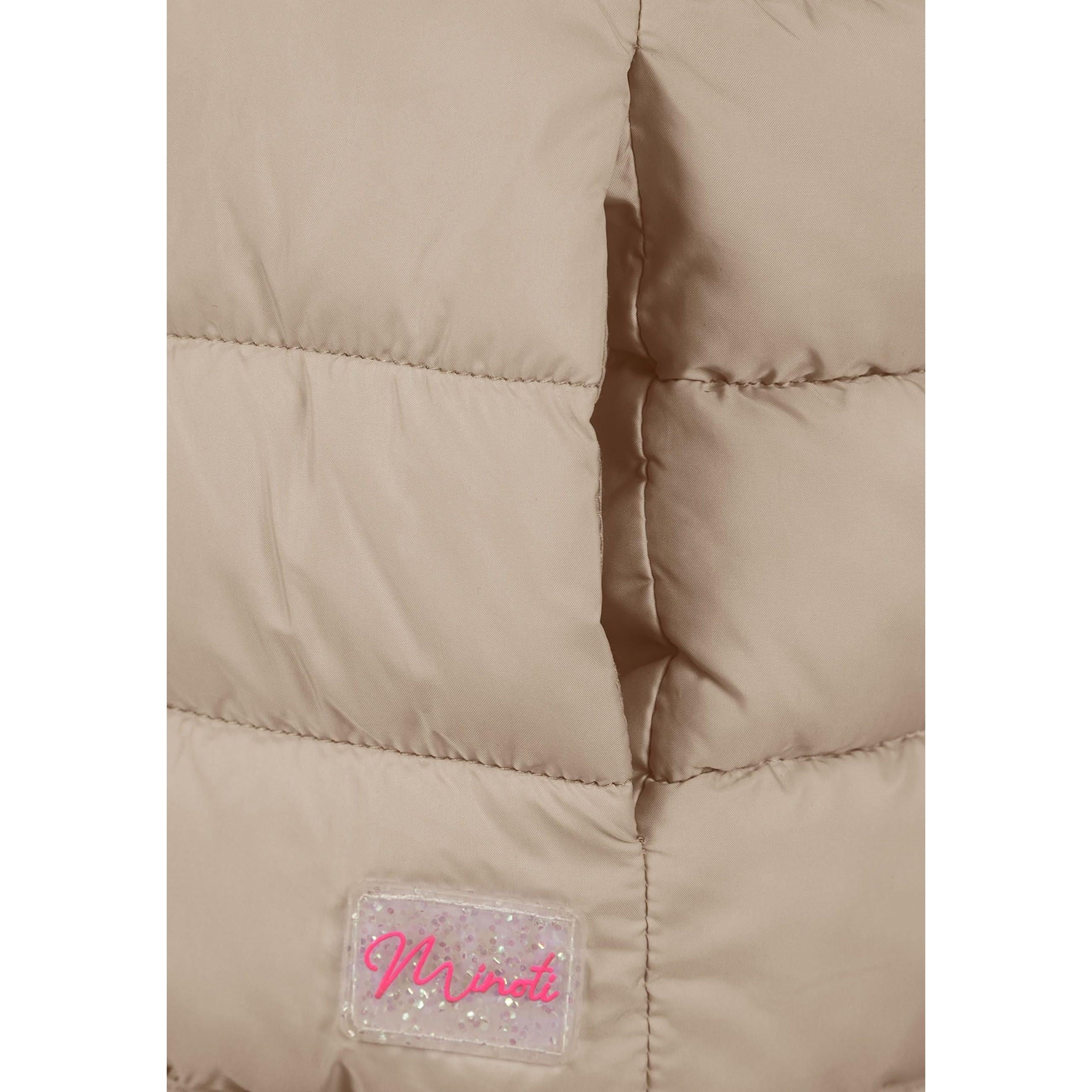 Close-up detail of beige quilted fabric showing horizontal stitching lines and Minoti brand label with pink lettering