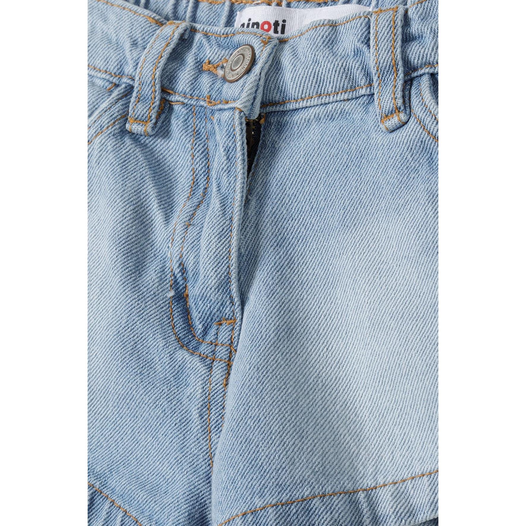 Close-up detail of denim shorts waistband showing Minoti brand label, button closure and front pocket construction