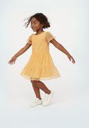 Cheerful girl in peach tiered girls party dress with sheer ruffled sleeves