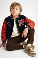 chłopiec w kurtce typu bomberka z haftowaną literą M na piersi i kontrastowymi rękawami