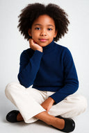 dziewczynka w granatowym klasycznym golfie i spodniami jeansowymi