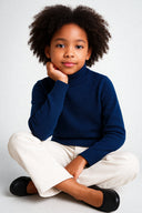 dziewczynka w granatowym eleganckim golfie i spodniami jeansowymi