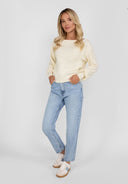 Woman in cream boat neckline jumper with jeans
